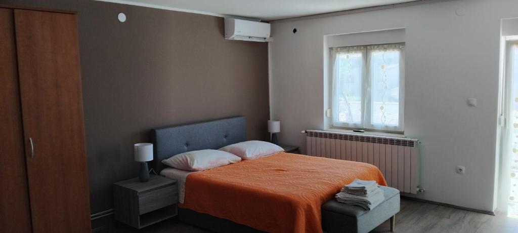 Room Benjamin في بوريتش: غرفة نوم بسرير وبطانية برتقالية ونافذة