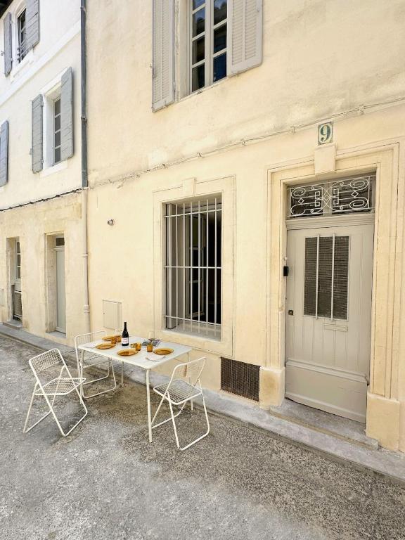 une table et des chaises devant un bâtiment dans l'établissement Maison de Charme Centre Roquette, à Arles
