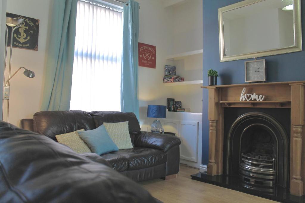 Bamber BridgeにあるYour lovely 3-bed home-from-home in Bamber Bridgeのリビングルーム(革張りのソファ、暖炉付)