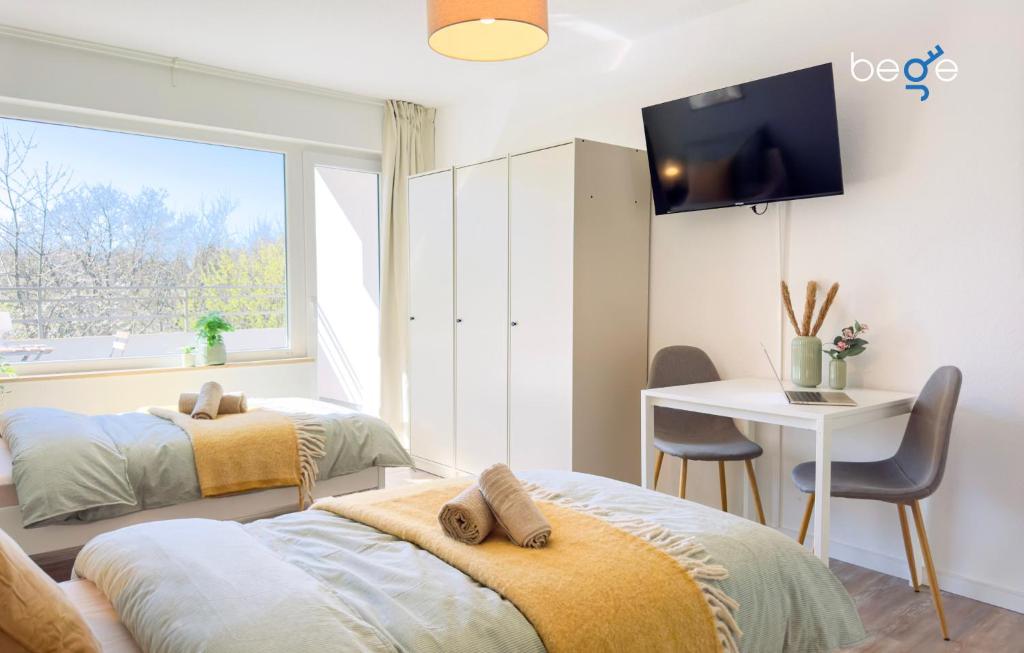 two beds in a room with a desk and a tv at BEGE APARTMENTS BizConnect in Wuppertal