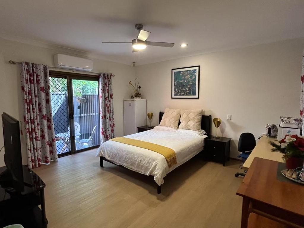 a bedroom with a bed and a desk and a window at Garden Retreat House Sunnybank Hills in Brisbane