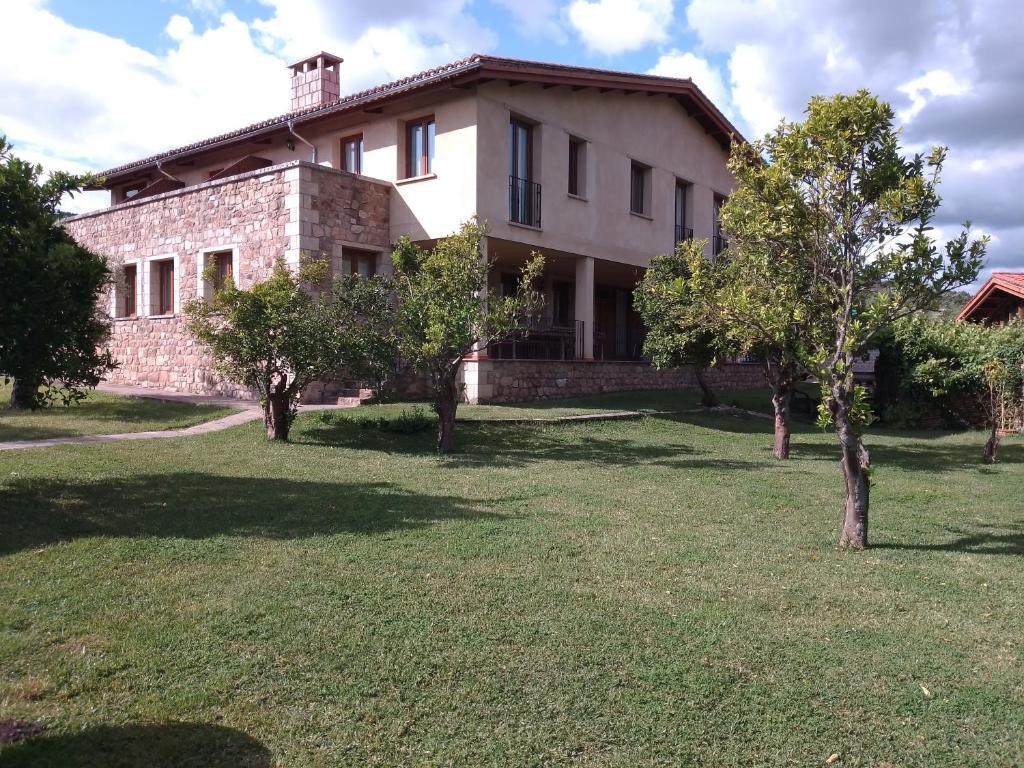 an old stone house with trees in the yard at Casa Rural La Flor del Naranjo in Cadalso