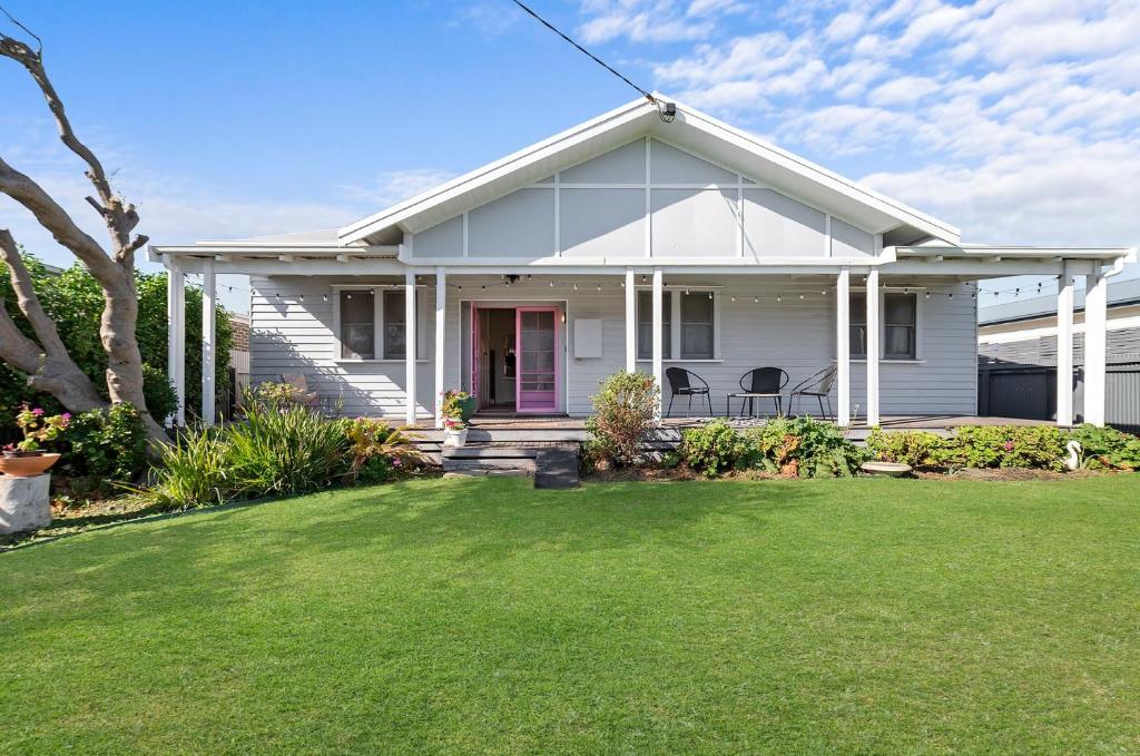 a white house with a red door and a yard at Seafield in Port Fairy