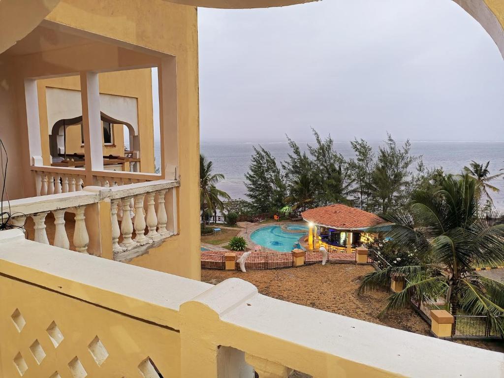 a balcony with a view of a pool and the ocean at Stunning beachfront 2 bedroom apartment in Mombasa