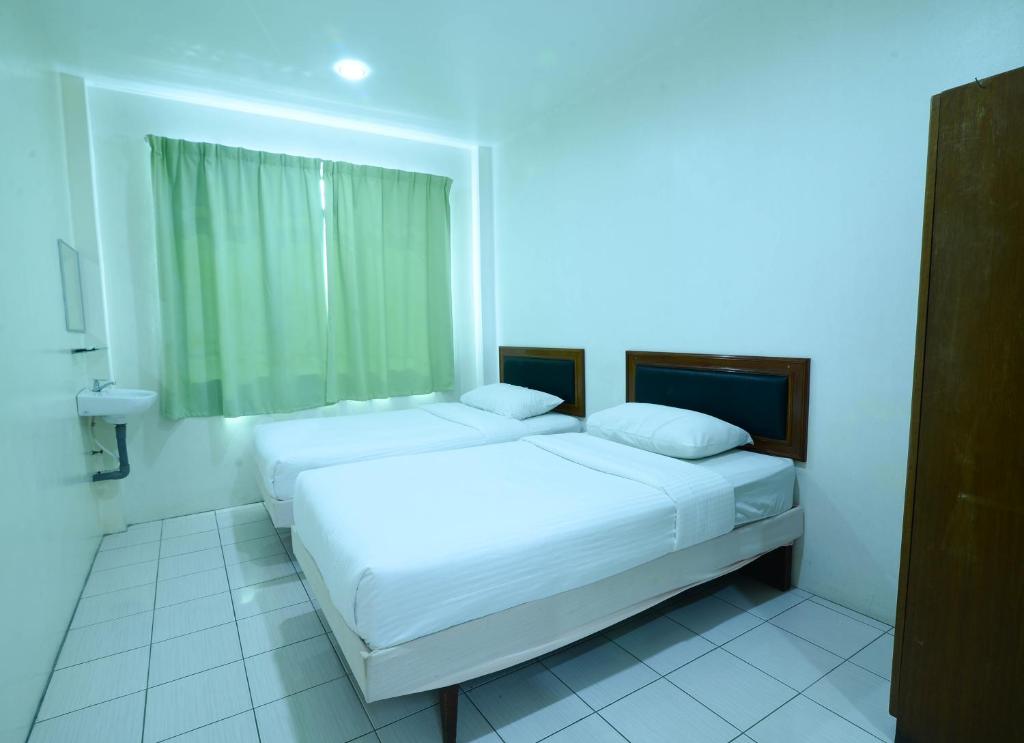 a bedroom with two beds and a blue light at Mersing Hotel in Mersing