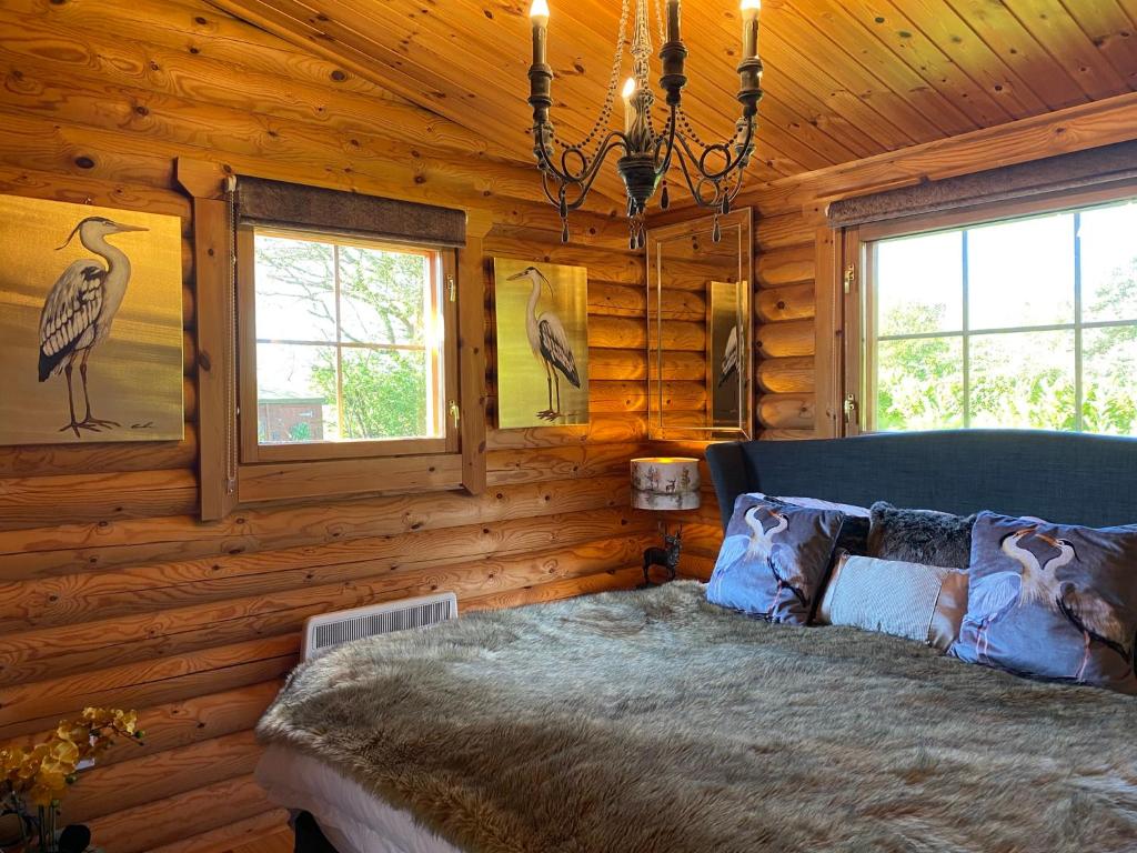 een slaapkamer met een bed in een blokhut bij Luxury Fishing Lodge - FatRascals Retreat in Hainford