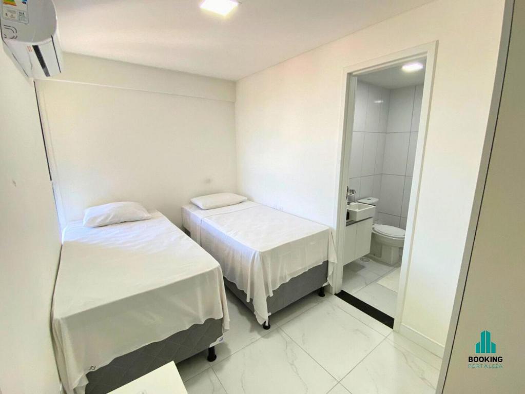 a small room with two beds and a bathroom at Fortaleza Sul Flats Service in Fortaleza