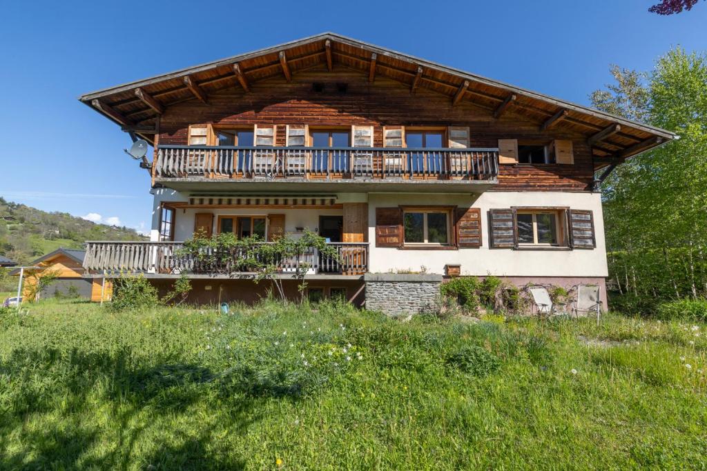 een groot huis met een balkon op een veld bij Appartement spacieux avec vue in Saint-Gervais-les-Bains