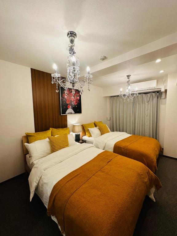 two beds in a room with a chandelier at Leopard Shinsaibashi 心斎橋 505 in Osaka