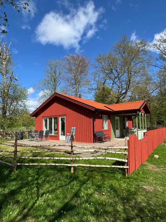 a red house with a fence in front of it at Meadow house, a comfortable and modern home near a lake in Ljungby