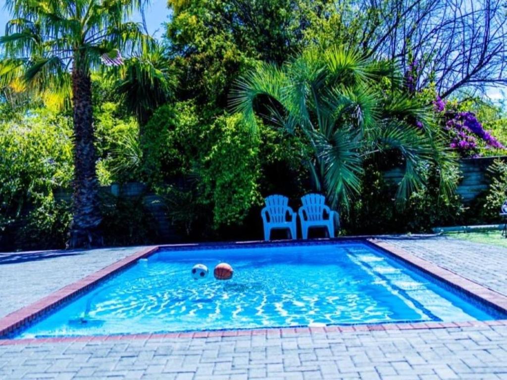 a swimming pool with two chairs and a ball in it at 5@Partridge Guesthouse in Newcastle