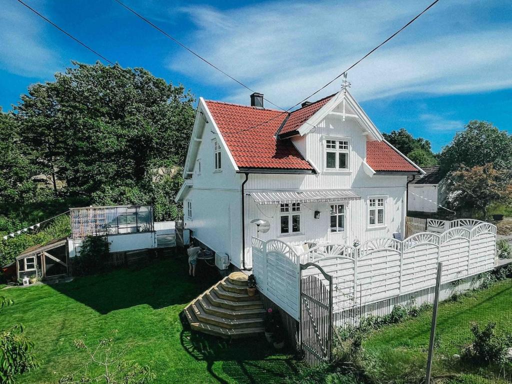 a white house with a fence in the yard at Unikt skipperhus med høner i hagen in Hvaler