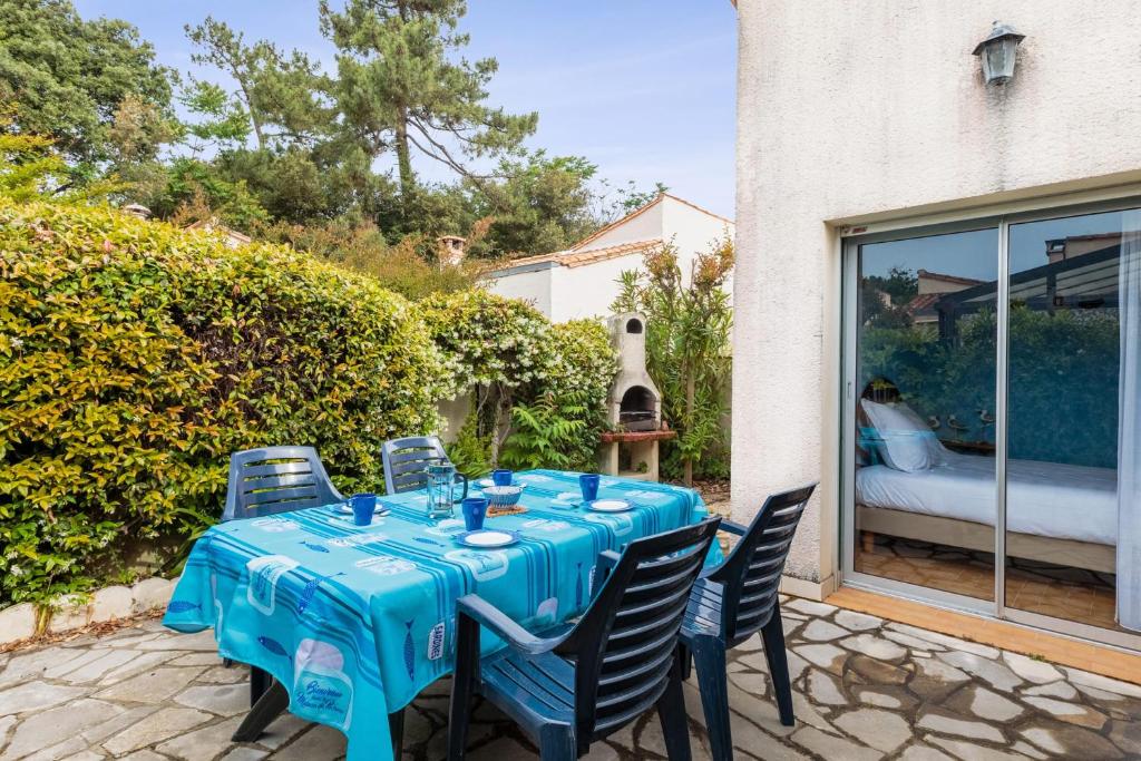 un tavolo e sedie blu su un patio di Maison aux Oiseaux - Welkeys a Dolus-d'Oléron