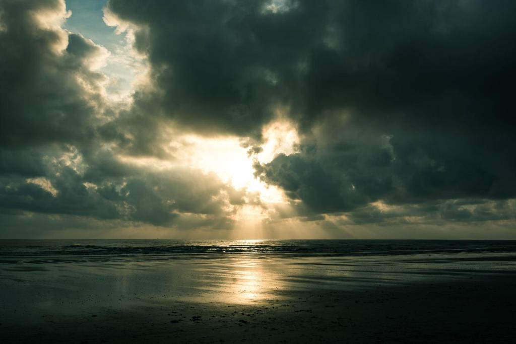 ein wolkiger Himmel über dem Strand mit der Sonne durch in der Unterkunft Holiday Homes At Samsuria Resort in Kampung Sungai Ular