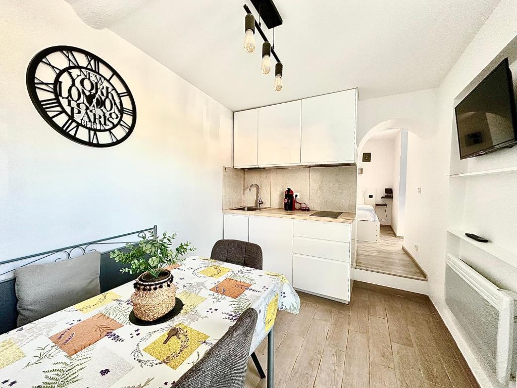une cuisine et une salle à manger avec une table et une horloge dans l'établissement Le Bastion-Plage-vue mer, à Menton