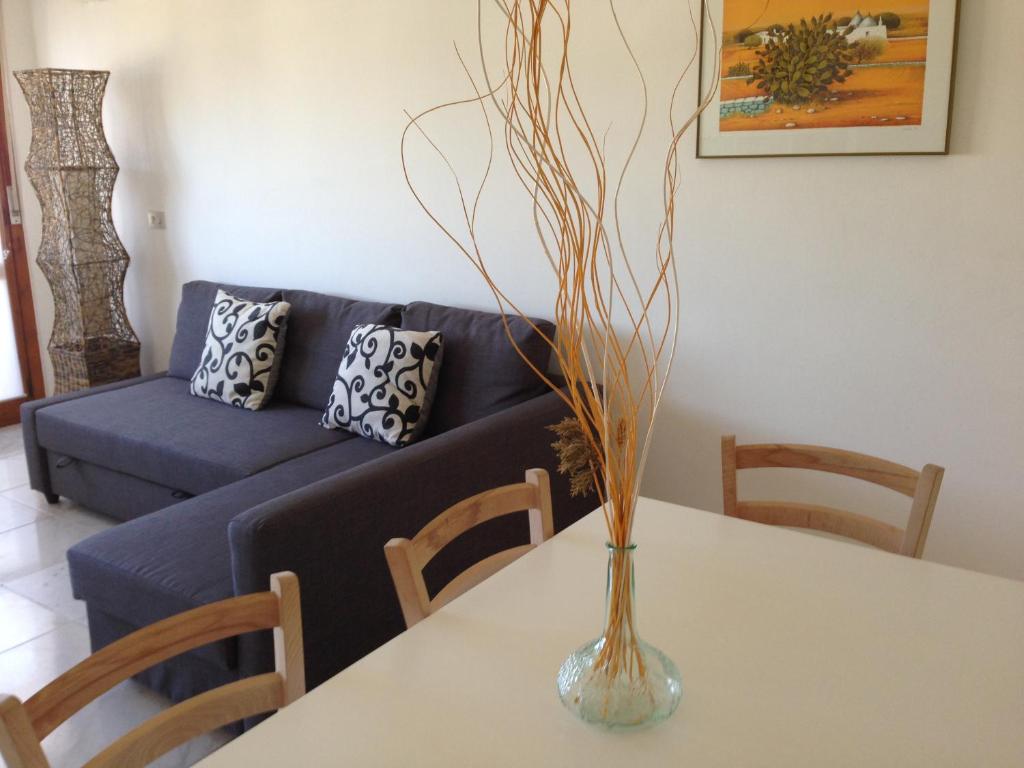 eine Vase auf einem Tisch mit einer blauen Couch in der Unterkunft Pace 27 in Alghero