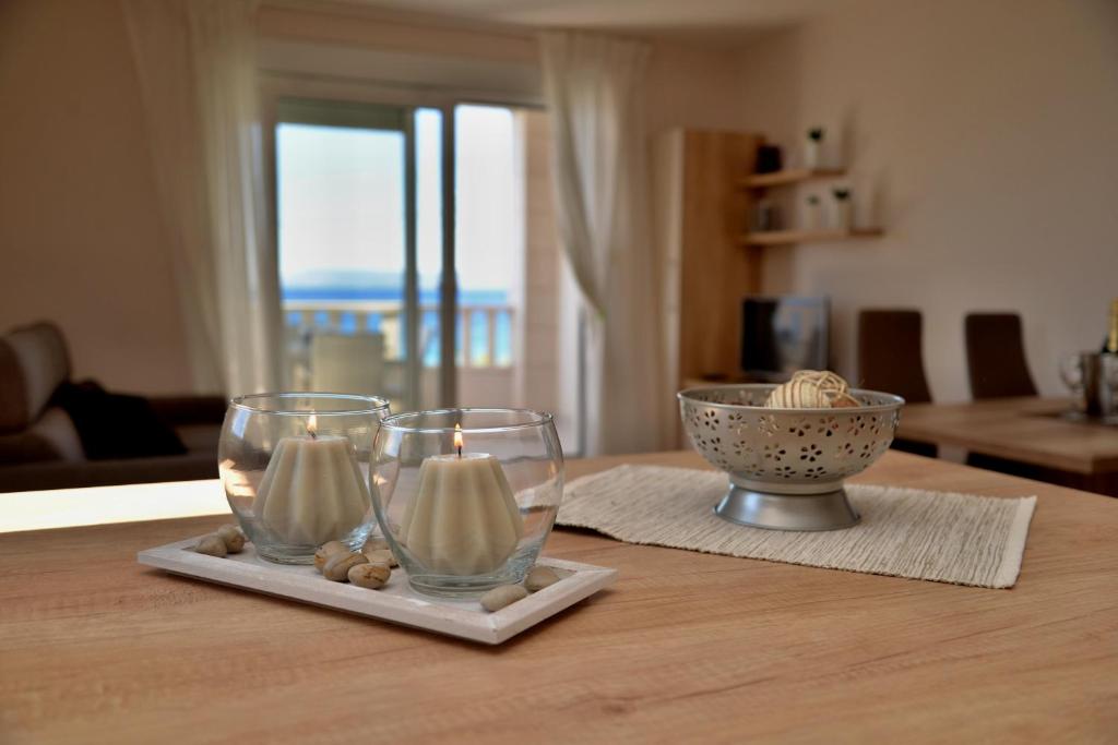 uma mesa com dois copos de vinho e uma taça de velas em Waterfront Apartments - Tucepi em Tučepi