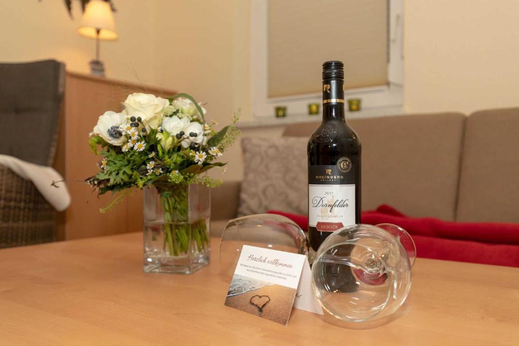 a bottle of wine and a vase of flowers on a table at Ferienwohnung Plogmann - Residenz Bernstein WHG 39 in Rerik