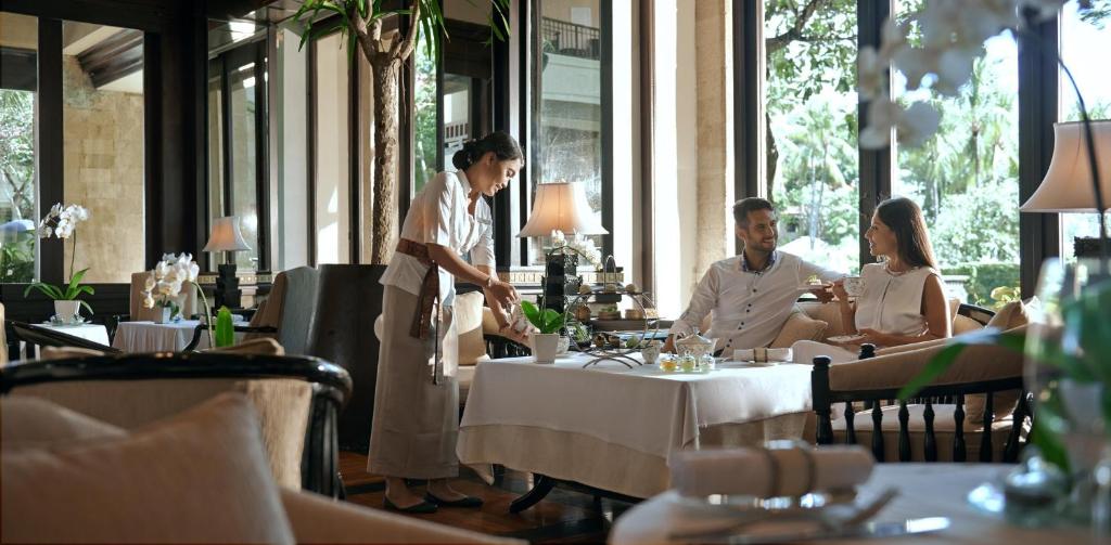 a group of people sitting at tables in a restaurant at InterContinental Bali Resort by IHG in Jimbaran