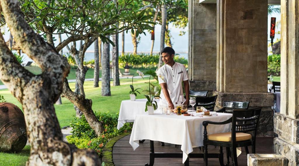 a man standing at a table at a restaurant at InterContinental Bali Resort by IHG in Jimbaran