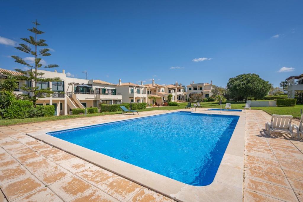 a swimming pool in a yard with houses at The Golden Breeze – Beachside Pool & BBQ Escape in Faro