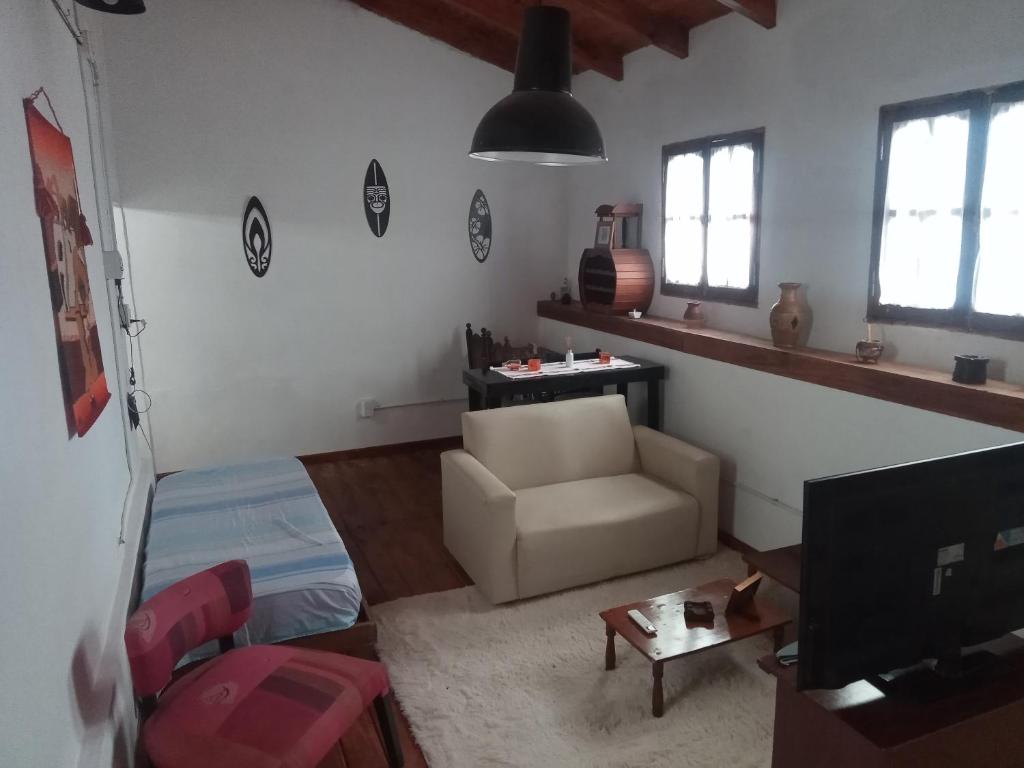 a living room with a couch and a chair and a tv at Mikasa in La Porteña