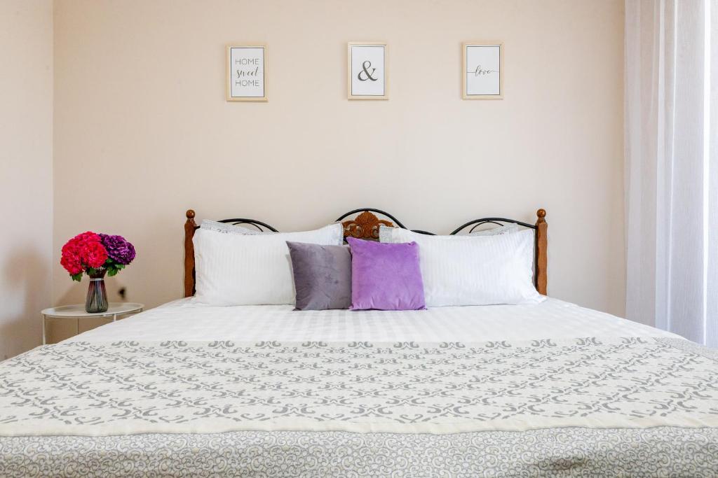a bedroom with a bed with purple and white pillows at Nexpo city apartments near Expo in Stroitelʼnyy