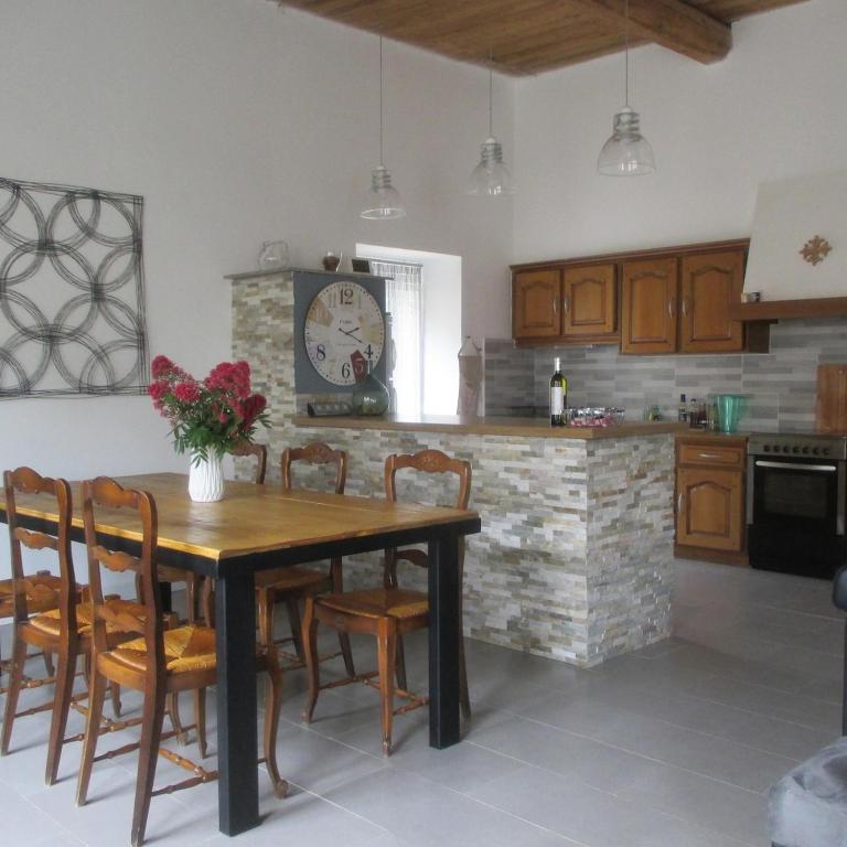 une cuisine avec une table, des chaises et une horloge dans l'établissement Maison entre CORBIÈRES et MINERVOIS, à Escales