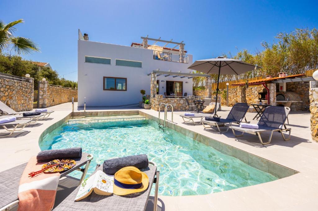 a swimming pool with chairs and a villa at Villa Melina in Tavronitis