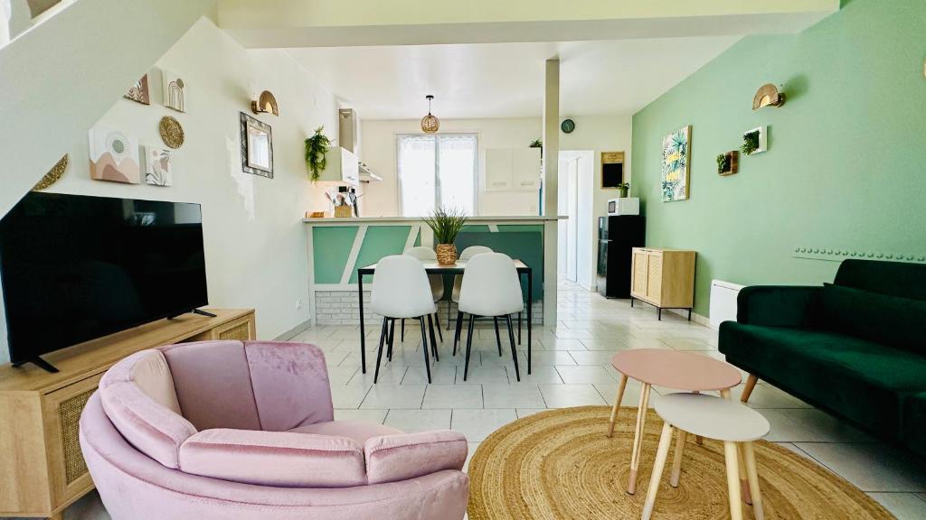 a living room with a pink chair and a table at Chez Mag maison de pêcheur proche plage in Ault