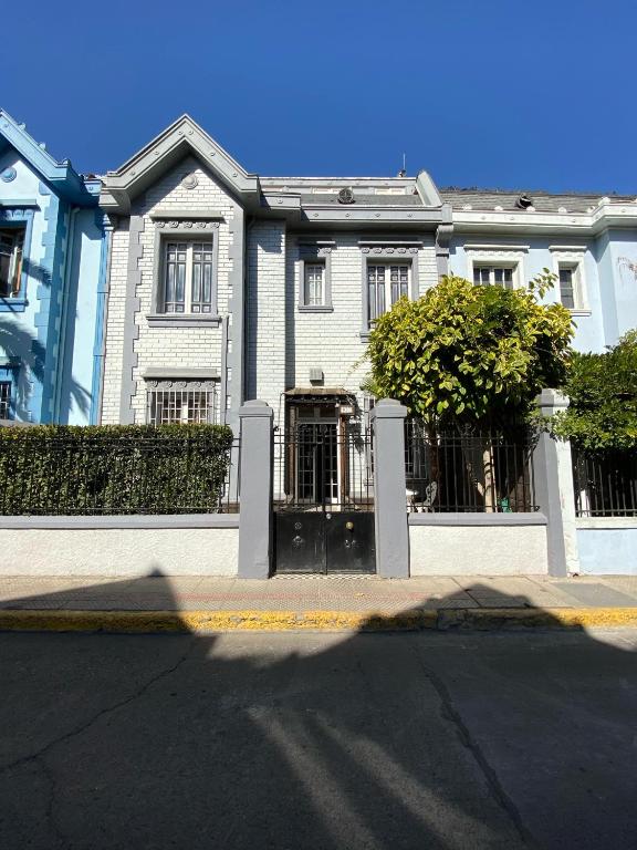 a white house with a fence in front of a street at Tremo Bustamante in Santiago
