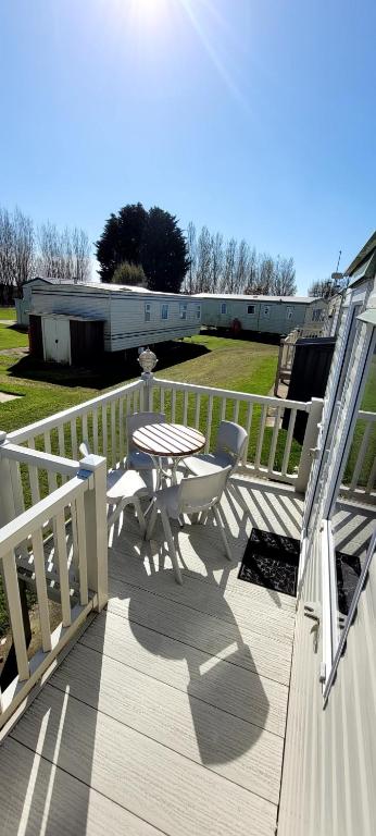 a wooden deck with a table and chairs on it at 4 Berth Static Caravan Golden Palm Resort with Decking in Chapel Saint Leonards