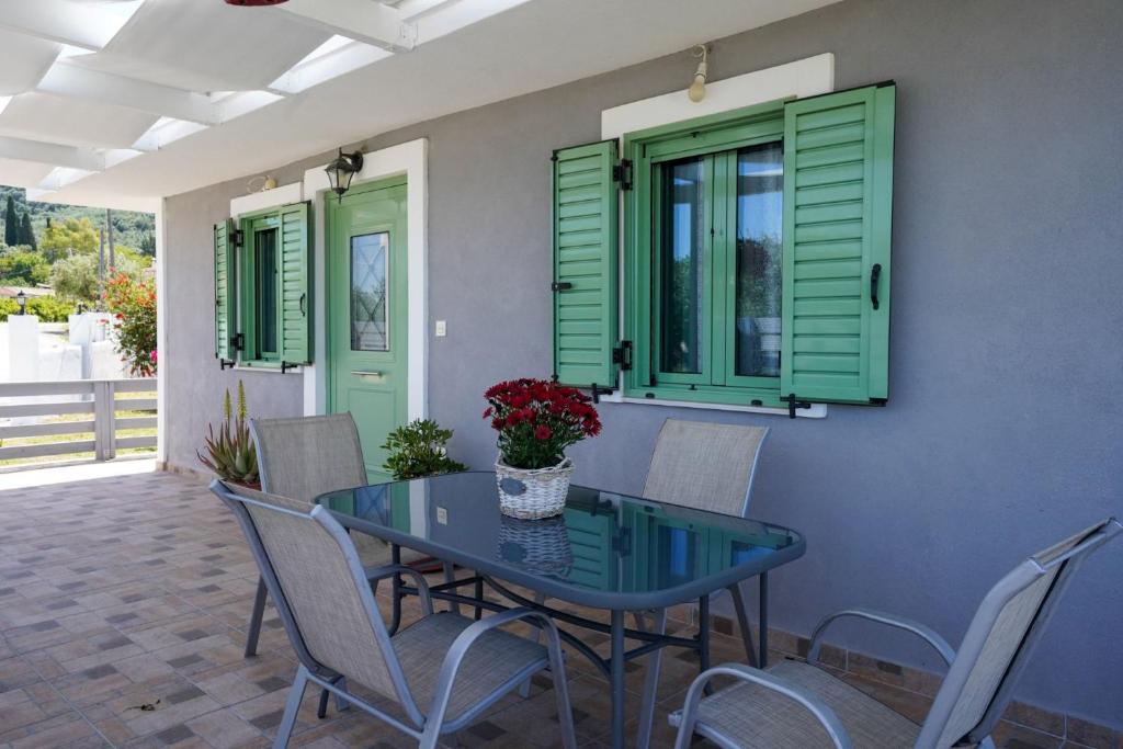 a table and chairs on a patio with green shutters at Mariettas Cottage in Pigadhákia