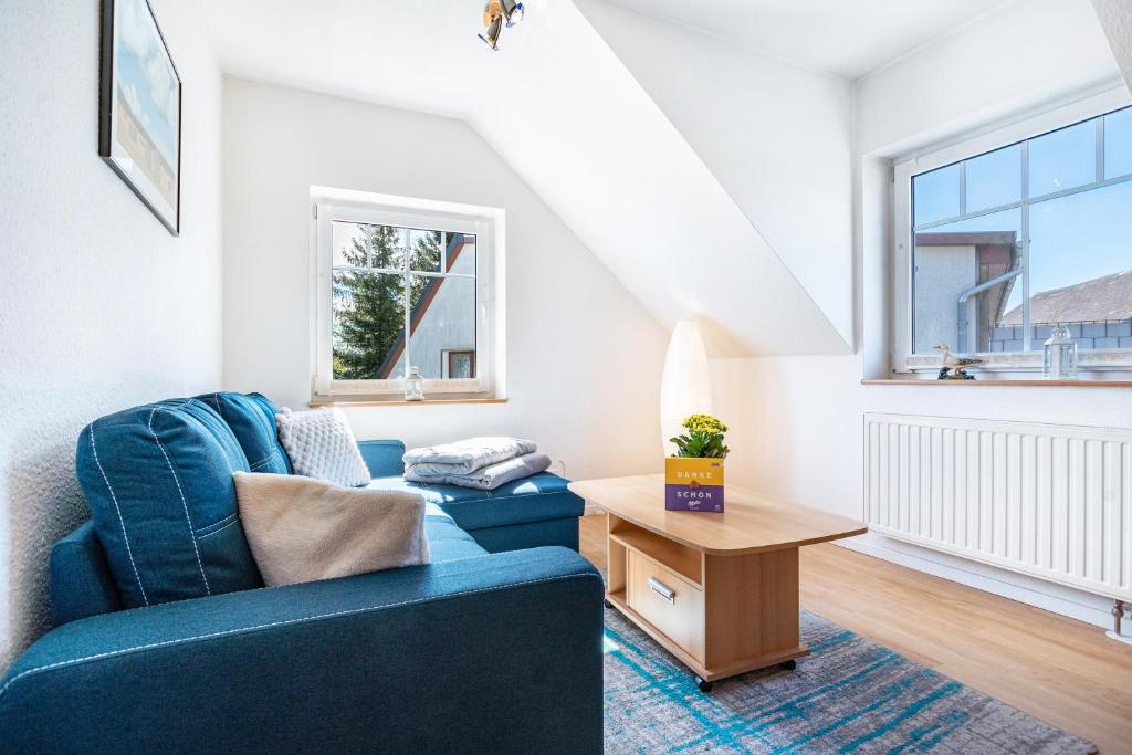 a living room with a blue couch and a wooden table at Ferienwohnung 2 in Groß Zicker