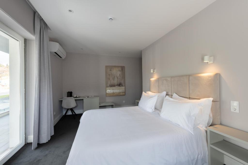 A double bedroom with a large bed, desk and full-height glazed opening.