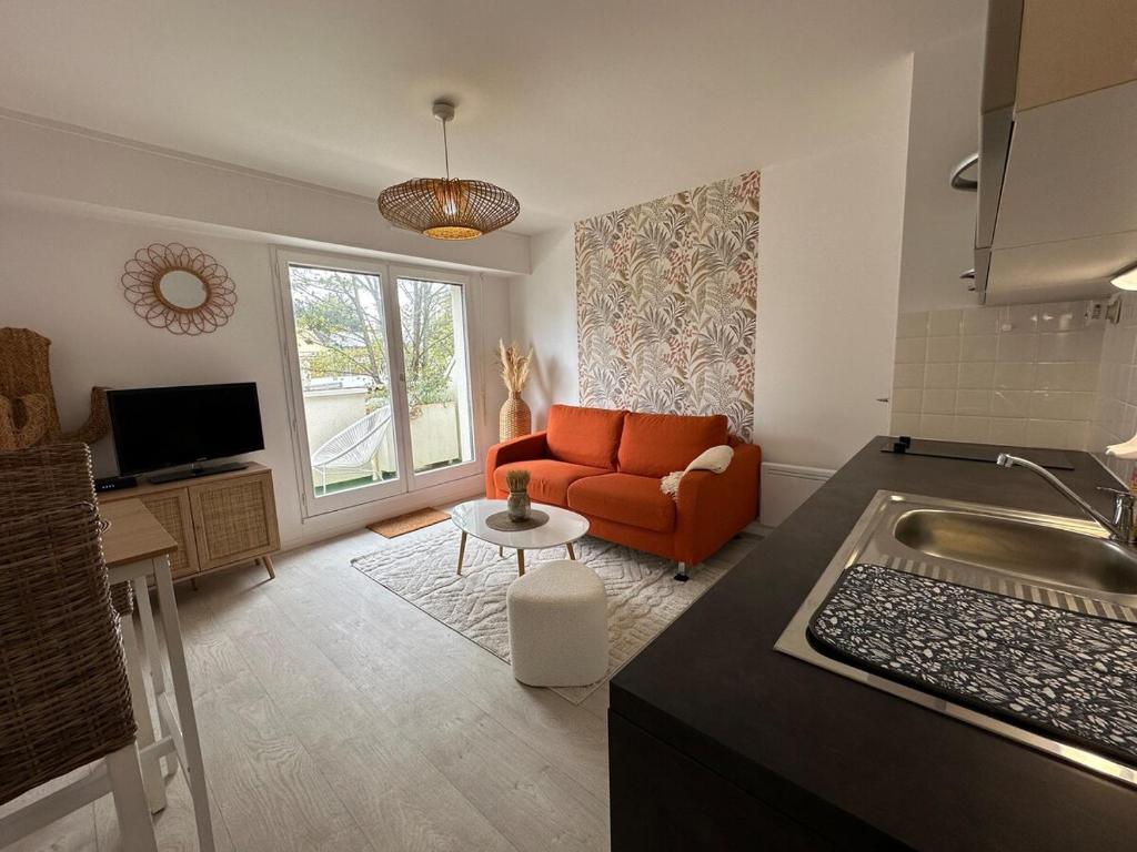 un salon avec un canapé orange et une table dans l'établissement Cocon proche du centre ville - balcon - parking, à Vannes