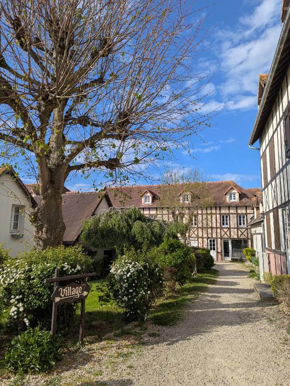 une maison avec un arbre et un panneau devant elle dans l'établissement Chez Camille, à Dives-sur-Mer