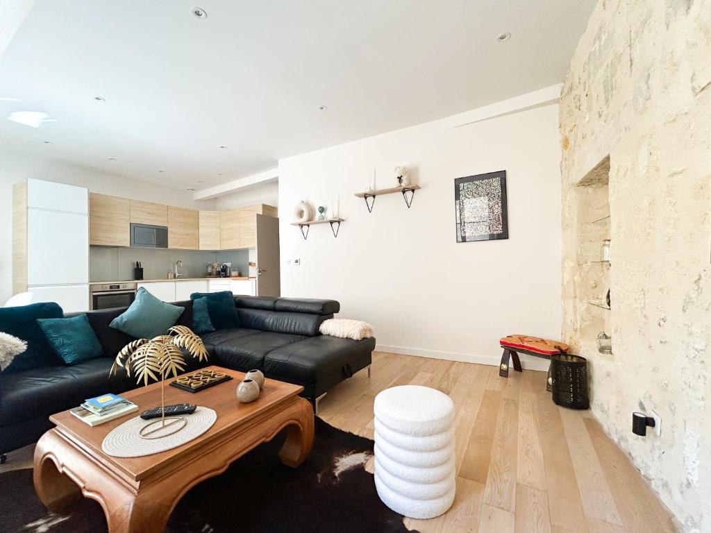 un salon avec un canapé noir et une table dans l'établissement Appartement Bordeaux centre, à Bordeaux