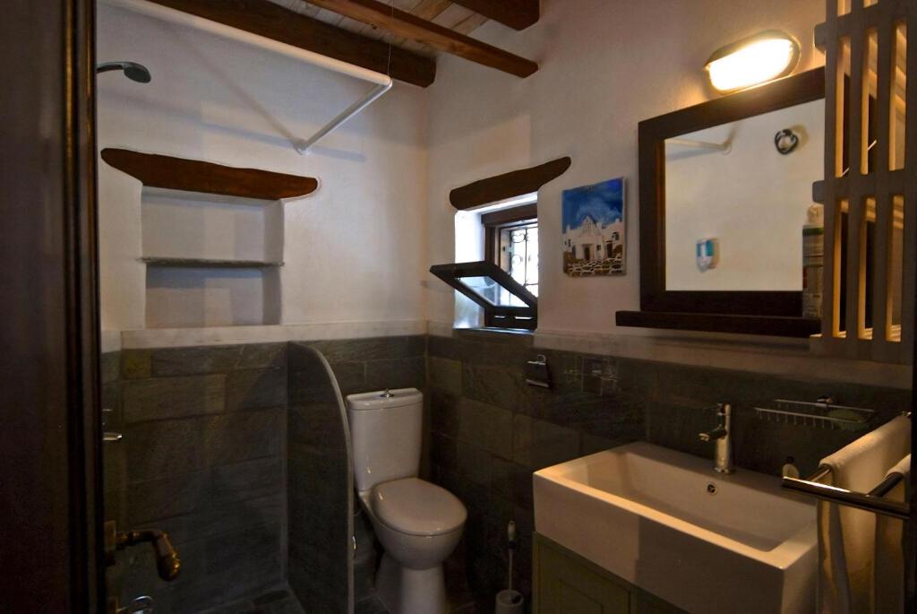 W łazience znajduje się toaleta, umywalka i lustro. w obiekcie Great Pelion Villa Villa Stone House 2 Bedrooms Sea View Aghios Georgios w mieście Pilion