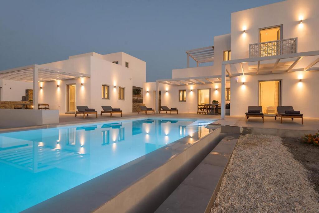 a villa with a swimming pool in front of a house at Beautiful Paros Villa 1 Bedroom The Calming Villa Wonderful Sea Views & Jacuzzi Naousa in Livadia