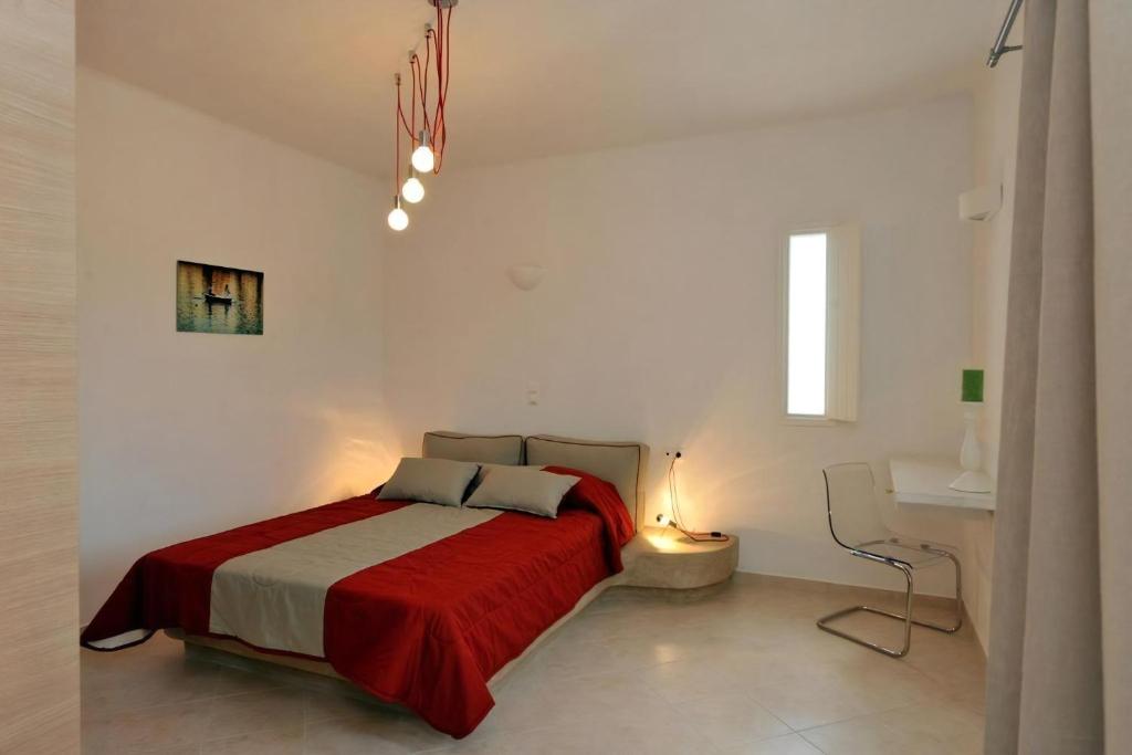 une chambre avec un lit avec une couverture rouge dans l'établissement Luxury Paros Villa 1 Bedroom Villa Vrachian Earth Private Jacuzzi & Beautiful Views Naousa, à Kampos Paros