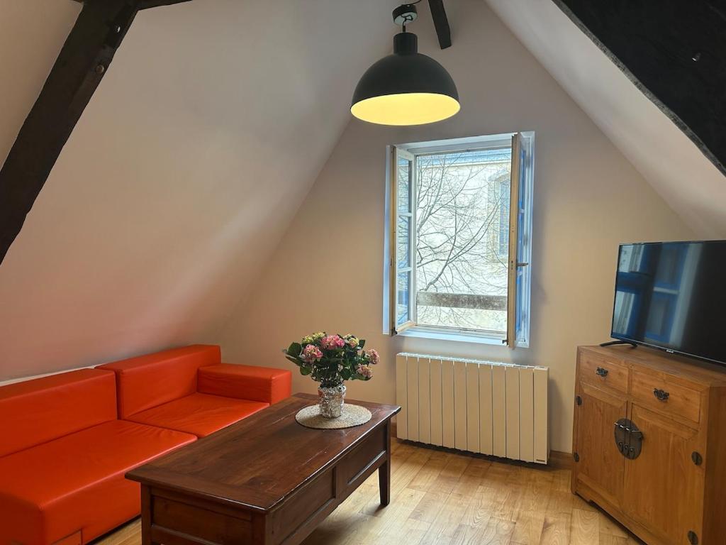 un salon avec un canapé orange et une télévision dans l'établissement T2 - Charme et confort au coeur de ville, à Vannes