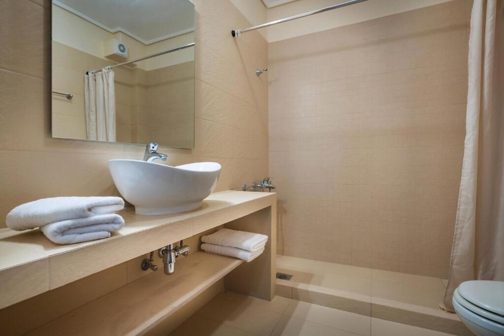 łazienka z umywalką, toaletą i lustrem w obiekcie Deluxe Kefalonia Apartment Apartment Lotos 3 Bedroom Sea View Karavomilos w mieście Karavomylos