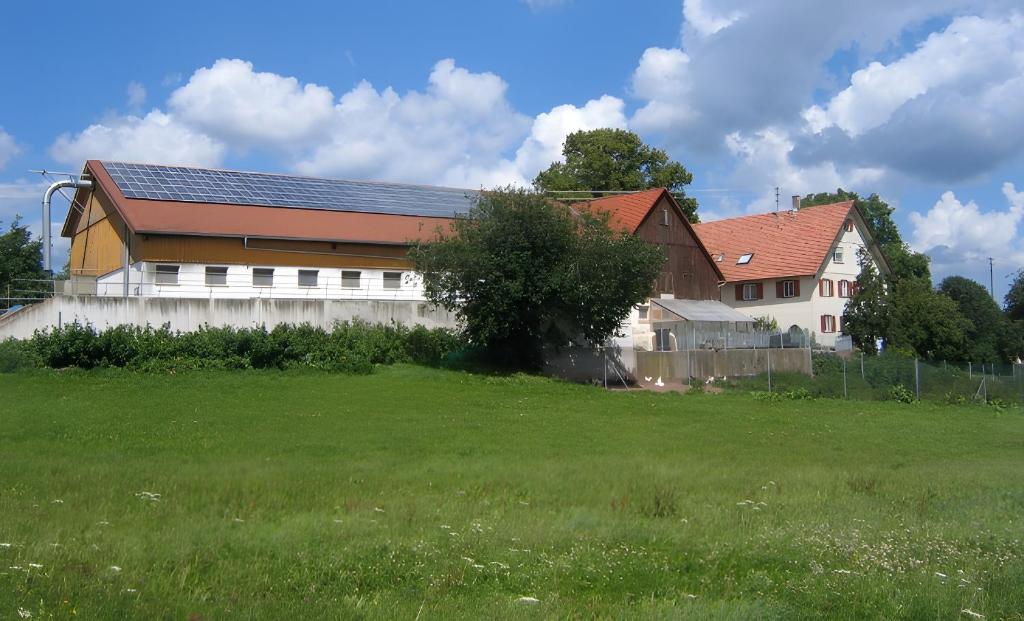 Un gran edificio con un campo de césped al lado de una casa. en Ferienhof Roller, en Simmersfeld