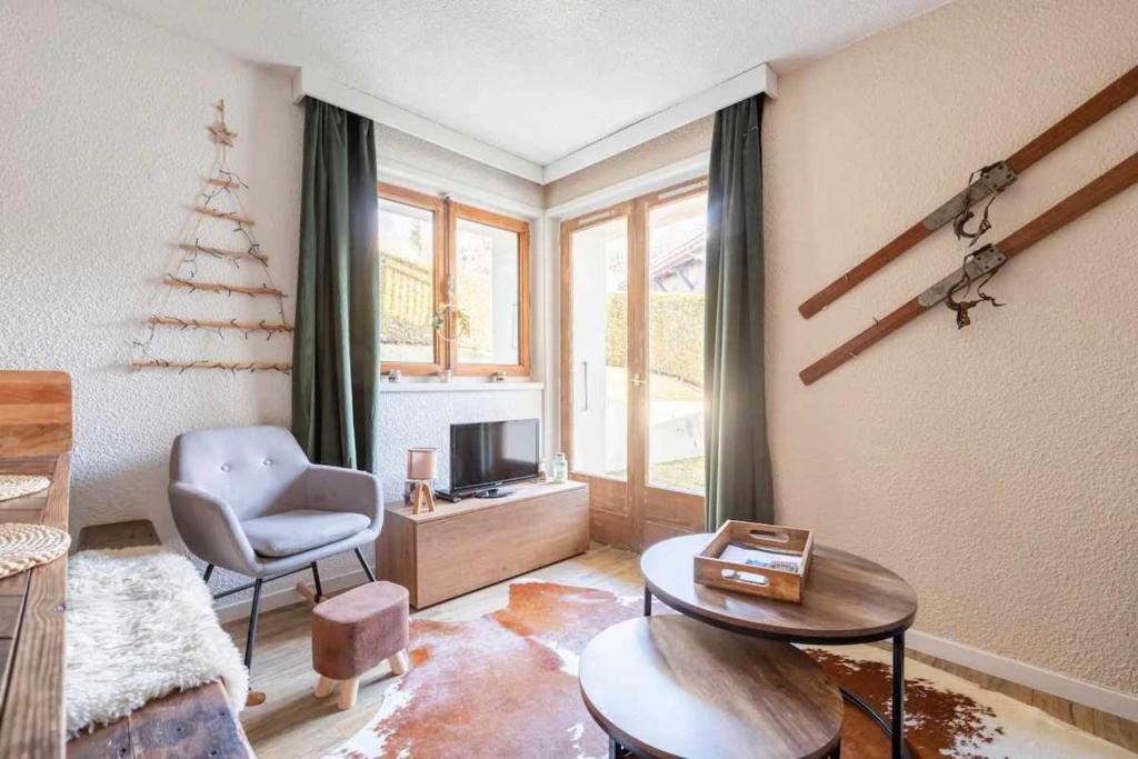 un salon avec une chaise, une table et une télévision dans l'établissement One-bedroom apartment with garden, à Megève