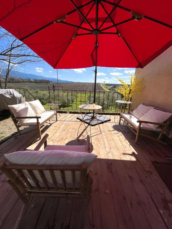 une terrasse avec un parasol rouge, des chaises et une table dans l'établissement Domaine de La Blache, à Saint-Jurs
