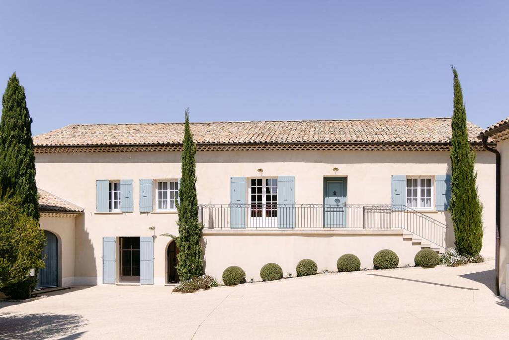 une grande maison avec un balcon et des arbres dans l'établissement Maison de charme au cœur des vignes, à Orange