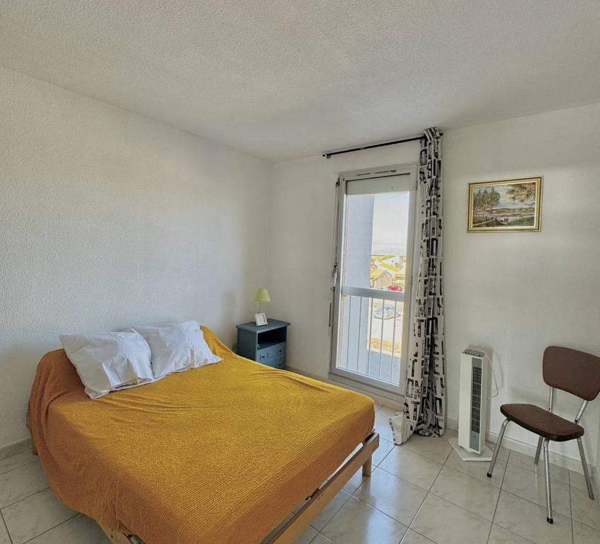 une chambre avec un lit, une fenêtre et une chaise dans l'établissement Appartement vue port et mer-4PPII26, au Barcarès