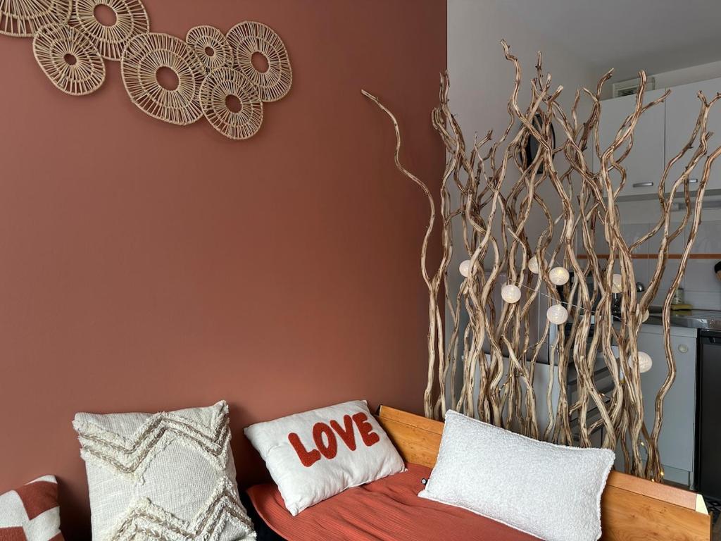 une pièce avec un canapé avec des oreillers et un arbre dans l'établissement Le Petit Pillon - studio avec parking, à Vannes