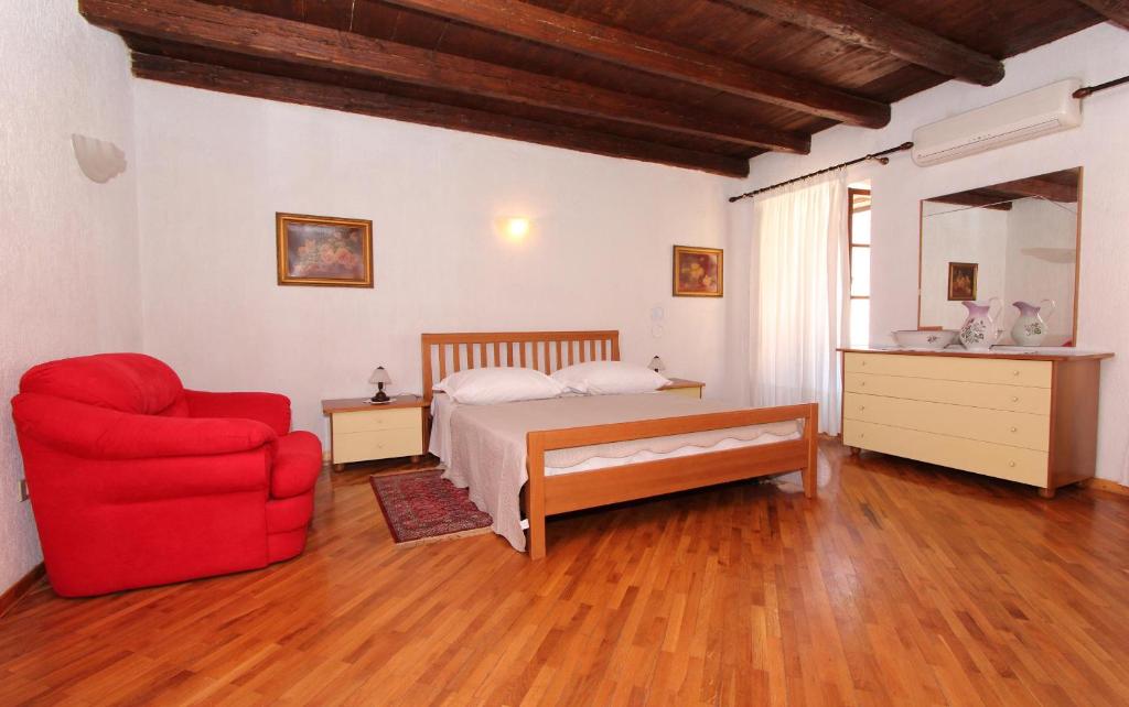 1 dormitorio con 1 cama y 1 silla roja en Apartments Ive, en Rovinj
